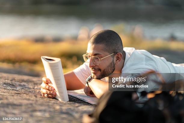 mens die een boek bij een picknick leest - leesbril stockfoto's en -beelden