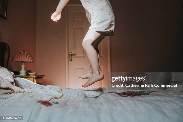 little girl jumping on an old fashioned bed - girl jumping stockfoto's en -beelden