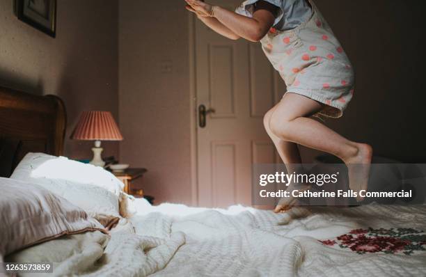 little girl jumping on an old fashioned bed - children jumping bed stock pictures, royalty-free photos & images