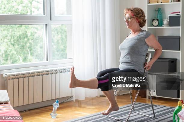 le donne anziane si esercitano a casa - sedia foto e immagini stock