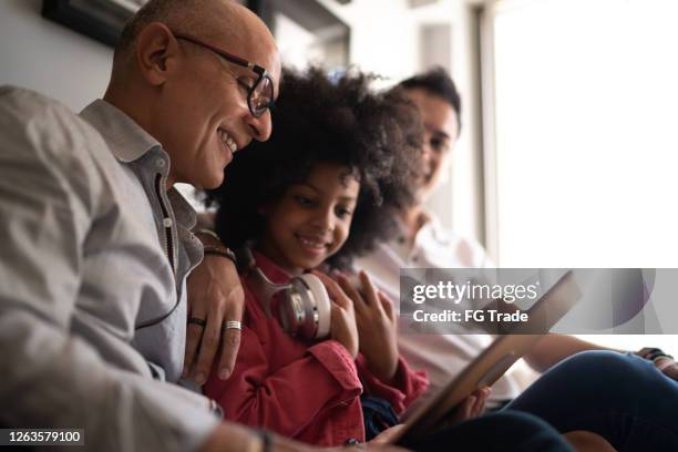 family reading on digital tablet together at home - foster care stock pictures, royalty-free photos & images