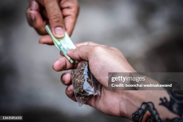 an addict with money buys a dose from a dealer on the street. addiction concept. - deal stockfoto's en -beelden