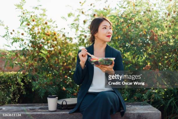 businesswoman having taking a lunch break outdoors - lunch lady foto e immagini stock