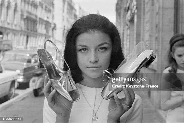 Mocassin et sandale or et plastique transparent, création du célèbre bottier Roger Vivier, à Paris, France le 26 juillet 1966.