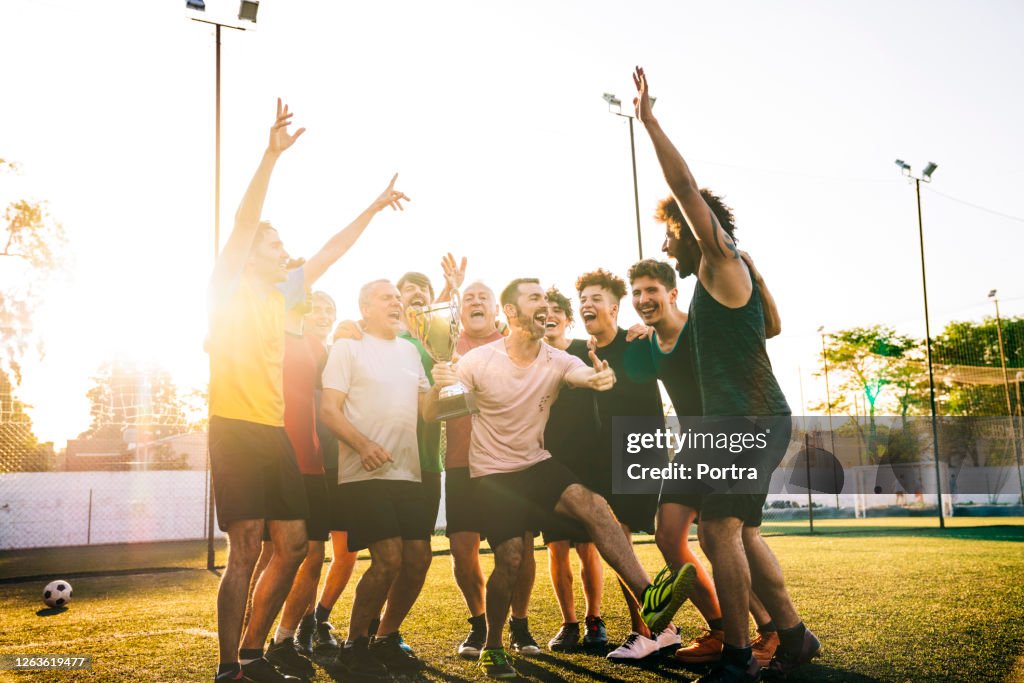 Happy players cheering with trophy in soccer ground