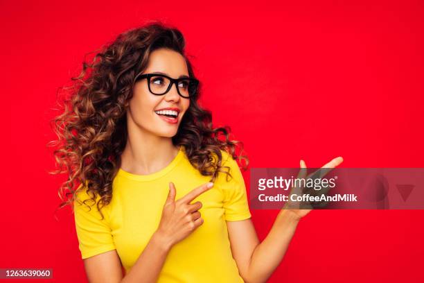 赤い背景に美しい女の子は彼女の指で正しい方向を示す - model tshirt ストックフォトと画像