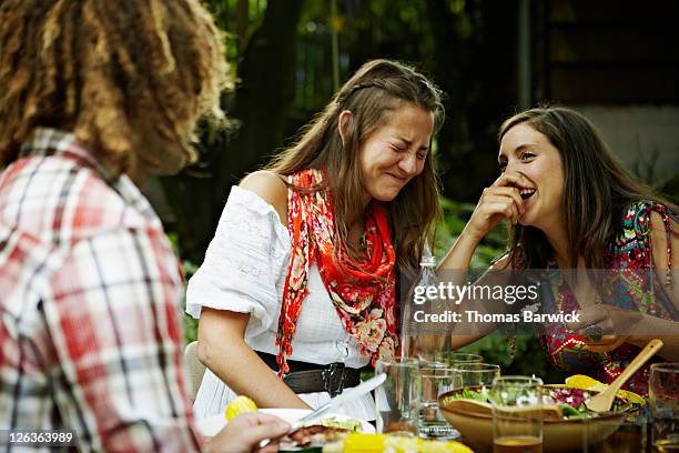 two women laughing together at dining table - outdoor entertaining stockfoto's en -beelden