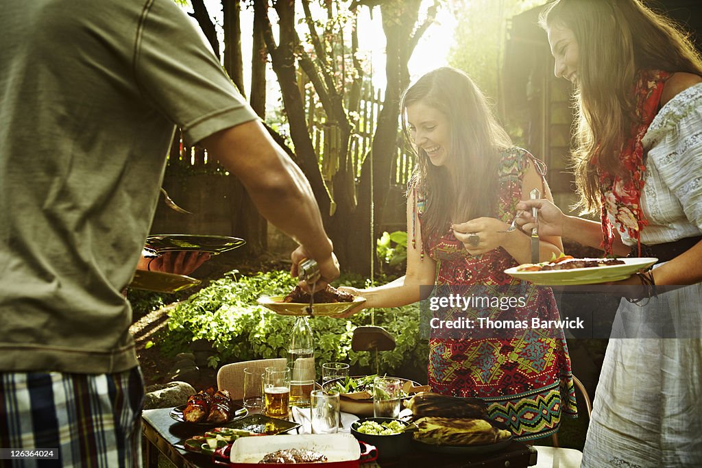 Group of friends dishing up food at table