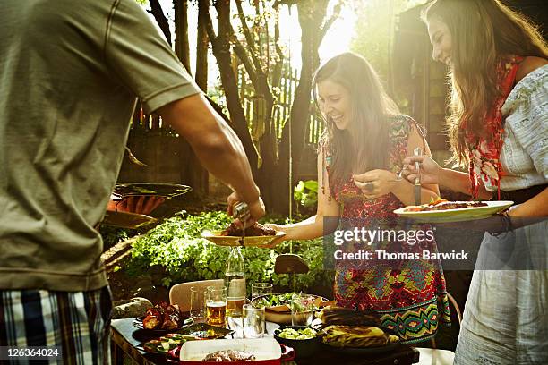 group of friends dishing up food at table - barbacoa amigos fotografías e imágenes de stock