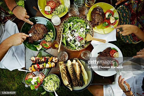 overhead view of friends dining at table outdoors - food stock pictures, royalty-free photos & images