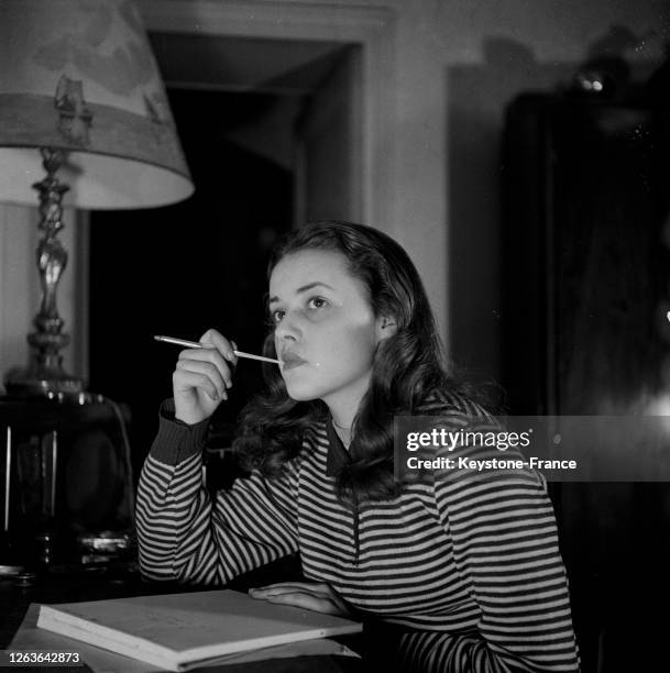 Jeanne Moreau, jeune comédienne de la Comédie française, photographiée chez elle travaillant à son bureau, à Paris, France, en 1948.