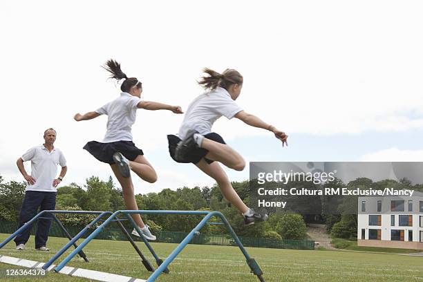students jumping hurdles in p.e. class - e girls stock pictures, royalty-free photos & images