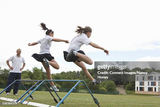 students jumping hurdles in p.e. class - train barriers stock pictures, royalty-free photos & images