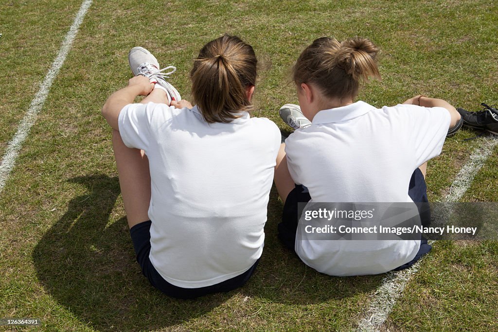 Girls lacing up soccer cleats outdoors