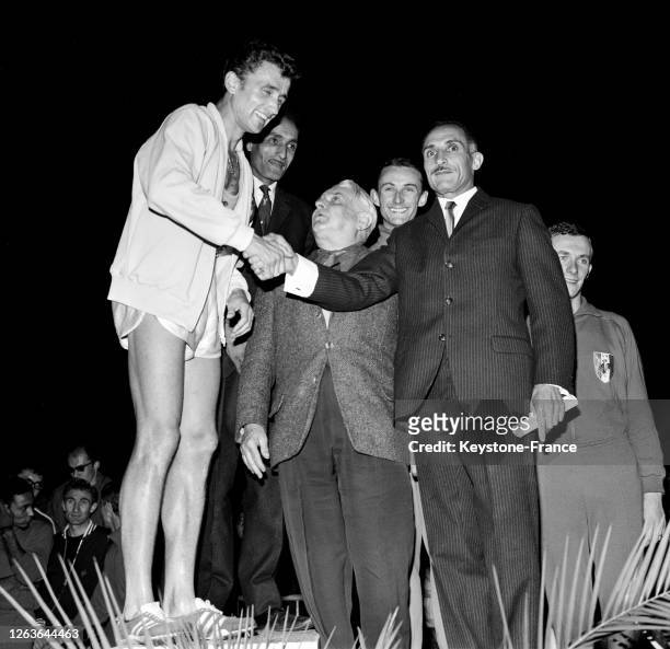Michel Jazy qui vient de pulvériser le record du monde, sur le podium, est félicité par Mimoun qui lui sert la main, à Saint-Maur, France le 13...