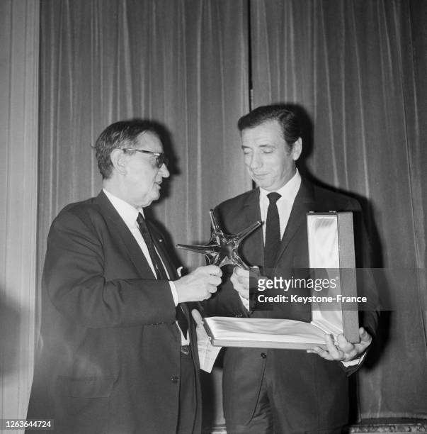 Georges Auric, Président de l'Académie du Cinéma, remet à Yves Montand reçoit une Etoile de cristal pour son interprétation dans 'La Guerre est...