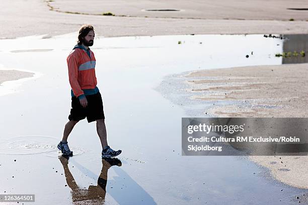 man walking through puddle in concrete - refshaleøen stock pictures, royalty-free photos & images