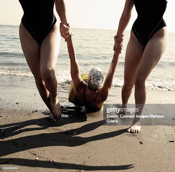 rescuers dragging swimmer to beach - redding sporten stockfoto's en -beelden