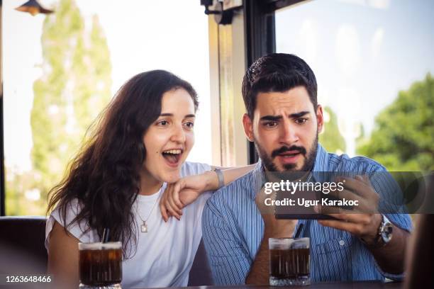 young couple looking smartphone screen - coffee express stock pictures, royalty-free photos & images