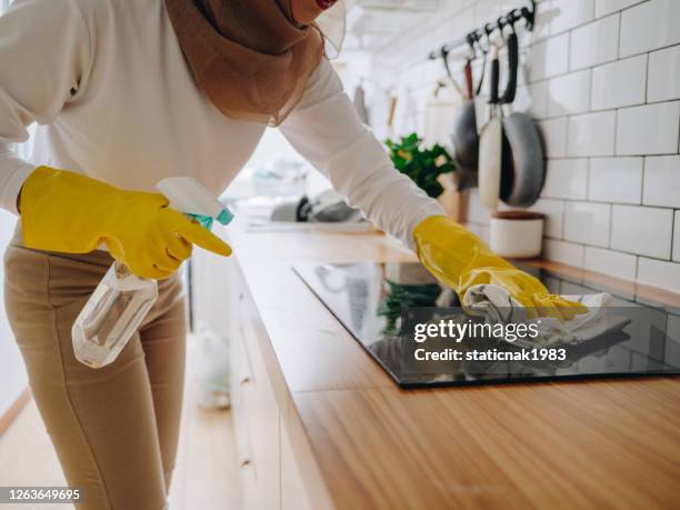 ragazza musulmana che pulisce il pannello di cottura del piano cottura in cucina. - piano del fornello foto e immagini stock