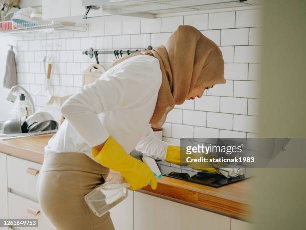 young muslim woman cleaning her kitchen counter top at home - infrared lamp stock pictures, royalty-free photos & images