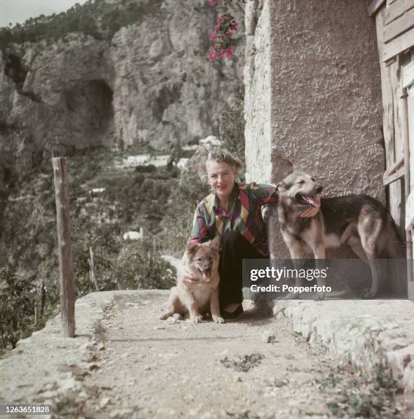 English actress and singer Gracie Fields posed with her two pet Alsatian dogs at her villa, La Canzone Del Mare on the Isle of Capri, Italy in...