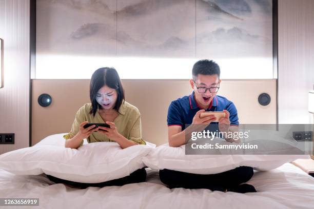 asian couple playing mobile game at bedroom at night - dating game stock pictures, royalty-free photos & images