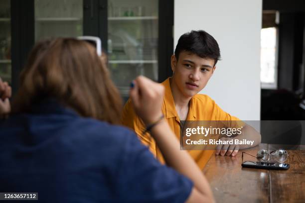 teenage boy chatting to his friends at the kitchen table - boy and girl talking stock pictures, royalty-free photos & images