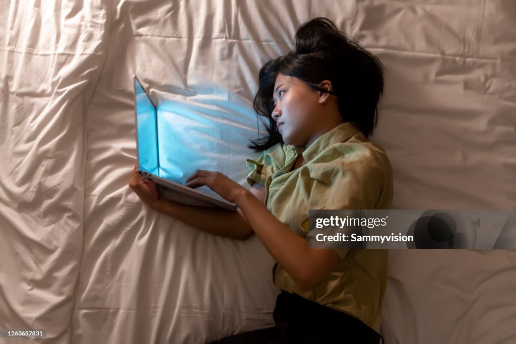 Asian woman working late at bedroom