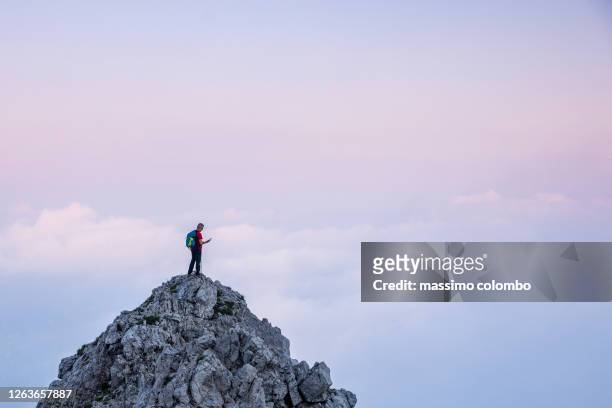 hiker man checking gps device on the top of mountain during twilight - tech summit stock pictures, royalty-free photos & images