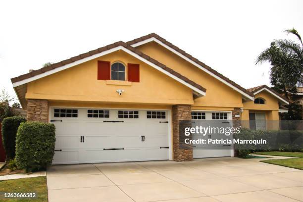 home exterior with carriage garage door - yellow door stock pictures, royalty-free photos & images