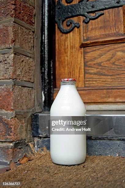 a traditional glass bottle of milk awaiting collection on doorstep. - milk bottle foto e immagini stock