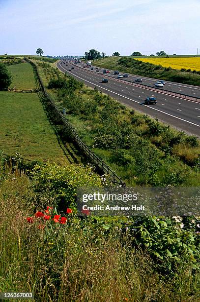 a view of the m40 motorway, flanked by poppies and fields of oilseed rape, as it cuts its way through oxfordshire. - craps stock pictures, royalty-free photos & images