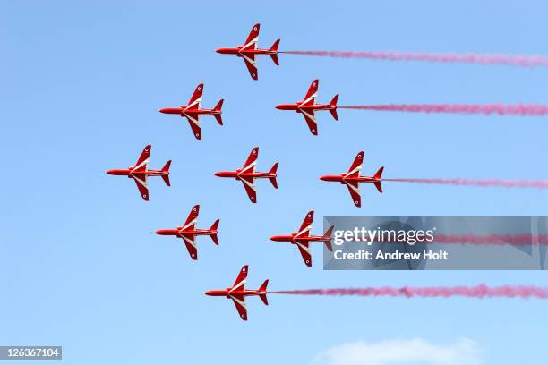 a dramatic view of the red arrows formation aerobatic flying team performing at the royal international air tattoo at raf fairford. acknowledged as one of the world's premier aerobatic teams, the red arrows are the public face of the royal air force. the - red arrow plane stock pictures, royalty-free photos & images