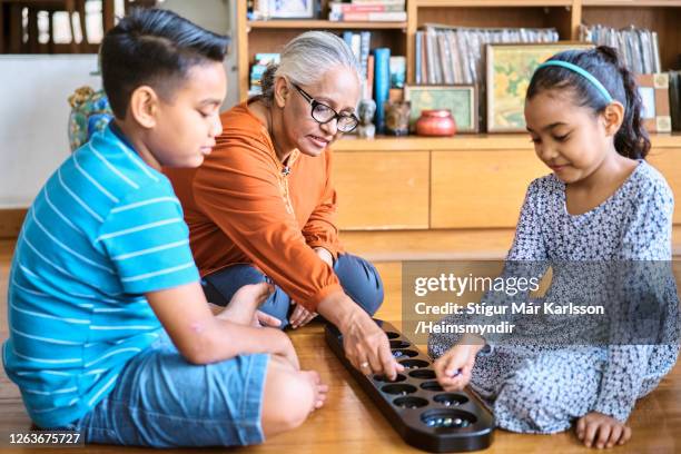 grootmoeder die spelen met haar kleinkinderen thuis speelt - mancala stockfoto's en -beelden
