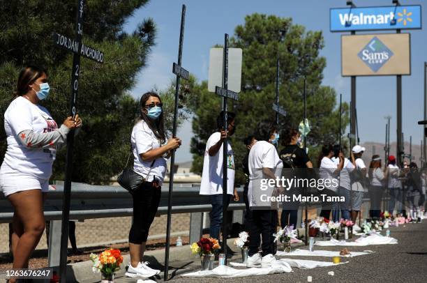 People hold 23 crosses in front of a Walmart honoring those killed in the Walmart shooting which left 23 people dead in a racist attack targeting...