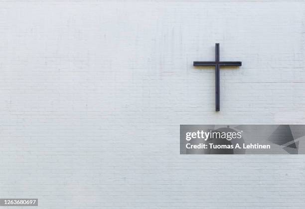 metallic cross on a white new plastered brick wall, viewed from the front. - cross section stock-fotos und bilder