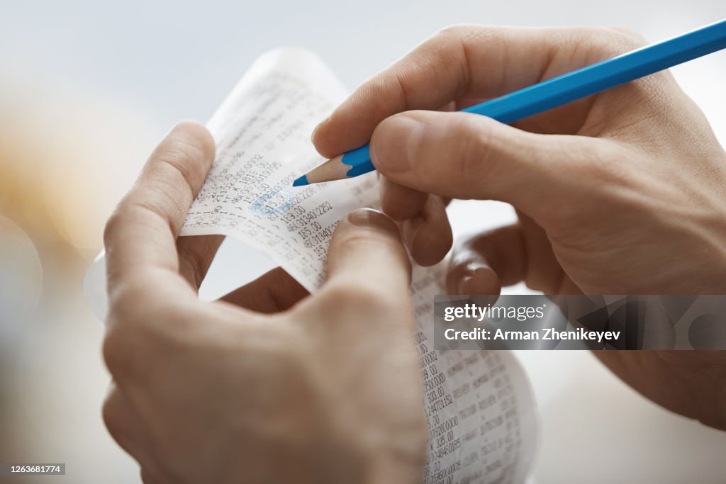 Human hands holding pencil and financial records