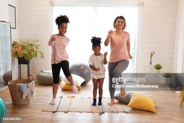 mother with two daughters cheerful to dancing exercising in living room - child mental health wellness foto e immagini stock
