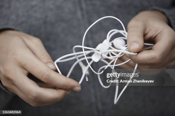 hands of human with tangled earphone wire - embaraçado - fotografias e filmes do acervo