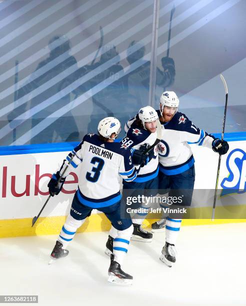 Jansen Harkins of the Winnipeg Jets celebrates his first NHL playoff goal with teammates Tucker Poolman and Adam Lowry in the first period against...