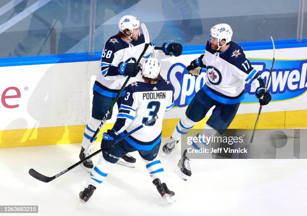 Jansen Harkins of the Winnipeg Jets celebrates his first NHL playoff goal with teammates Tucker Poolman and Adam Lowry in the first period against...