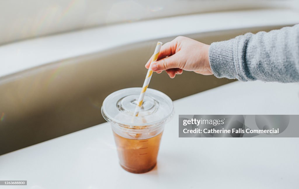 https://media.gettyimages.com/id/1263688800/photo/clear-plastic-cup-half-full-of-iced-coffee-with-a-paper-straw-hand-reaches-for-the-straw.jpg?s=1024x1024&w=gi&k=20&c=iGms2zYHBepVPZy0wH18kP63pR9yNT3TfEmvvYlIw4w=