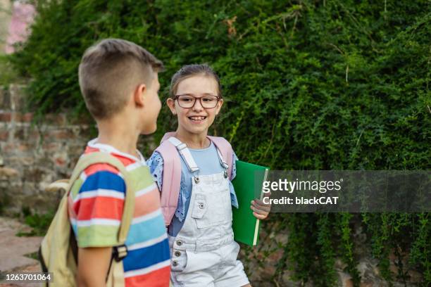 los niños van a la escuela - boy and girl talking fotografías e imágenes de stock