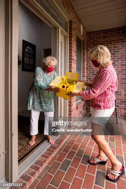 delivering a box of treats to a senior woman - care package stock pictures, royalty-free photos & images