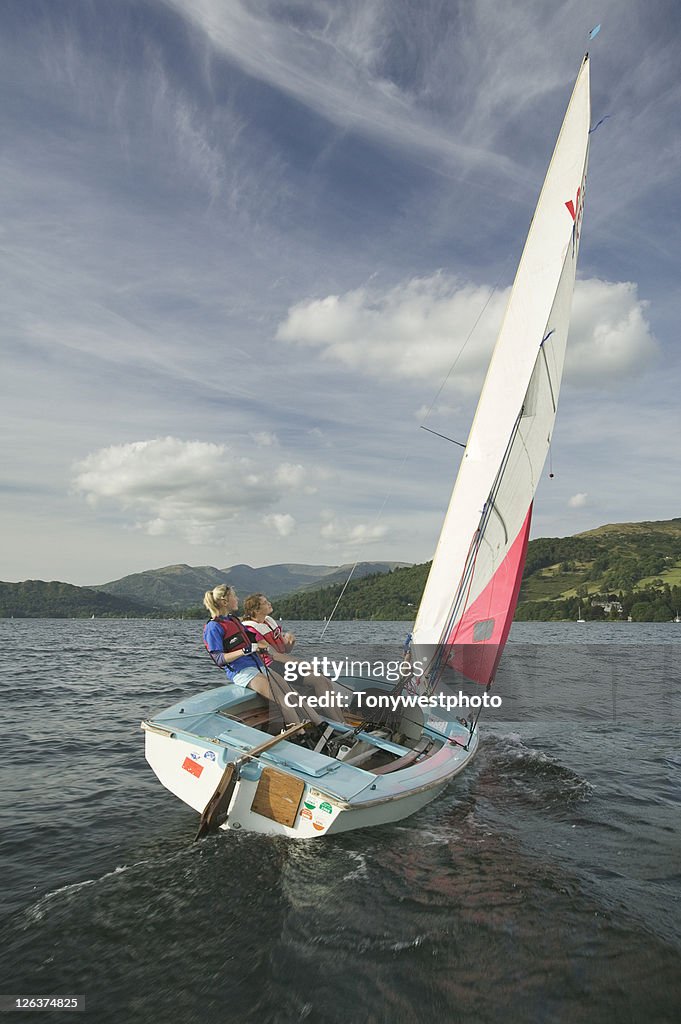 Two girls sailing dinghy on lake Windermere.