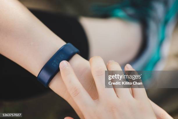 asian woman checking her heart rate on a smart watch - handgelenksschweißband stock-fotos und bilder