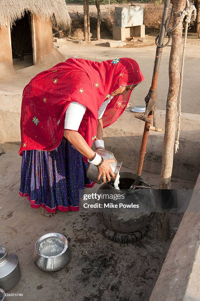  Bishnoi woman pouring curd into vessel to make cheese, Rajasthan, India