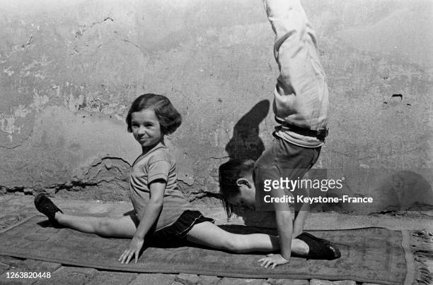 Jeune fille de petite taille faisant le grand écart et un petit garçon acrobate en 1936 à Paris, France.