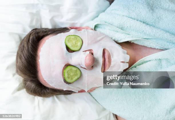 man face under cosmetic mask. an elderly man made a cosmetic mask at home. relaxation and body care at home. - mask stock-fotos und bilder